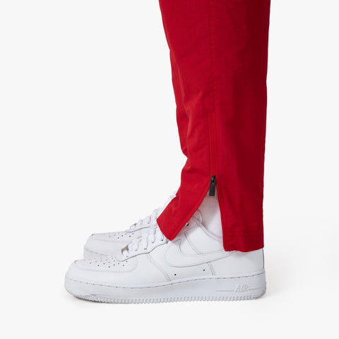 adjusted zipper on leg of the tapered 100 Thieves Foundation nylon pants in the color red